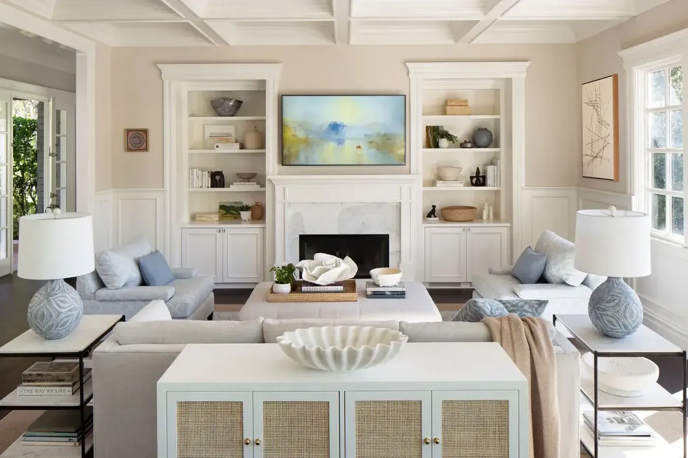 A bright and cozy coastal-inspired living room in Singapore with a white sofa, built-in bookshelves, and a woven console table.  Image Caption: Use a short, engaging caption to provide context and encourage user engagement.