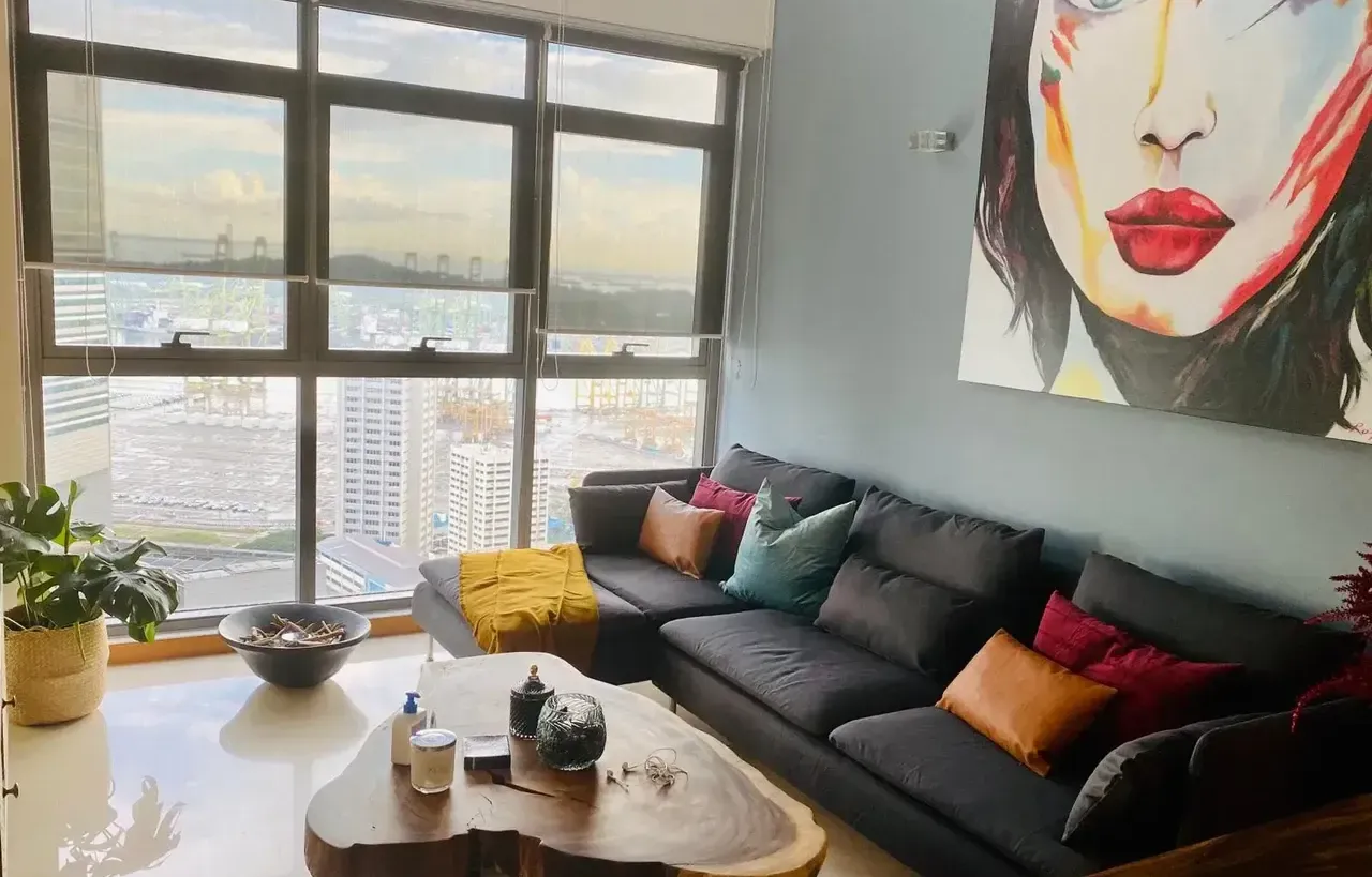 A cozy, modern living room with a dark sectional sofa, colorful throw pillows, and a unique live-edge coffee table.