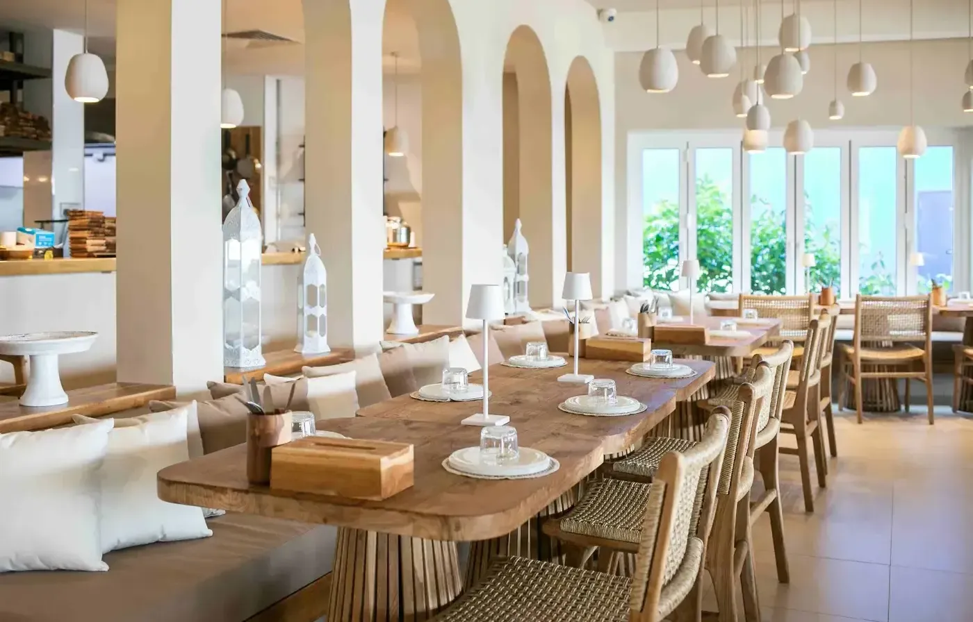 A luxurious bohemian dining room featuring a stunning live-edge wooden table, natural light, arched doorways, and sophisticated pendant lighting.