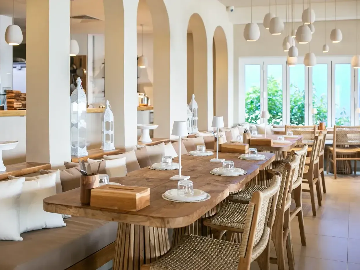 A luxurious bohemian dining room featuring a live-edge wooden dining table, arched doorways, and elegant lighting.
