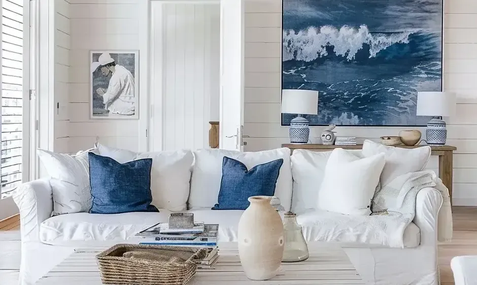 A serene, coastal-themed living room with a blue and white color palette, throw pillows, and nautical-inspired wall art.