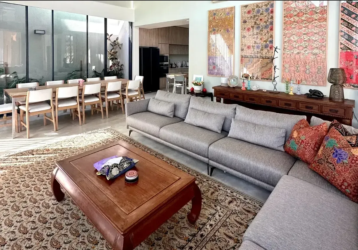 A bright and spacious modern living room in Singapore with a gray sofa, a wooden coffee table, and large-scale wall art.