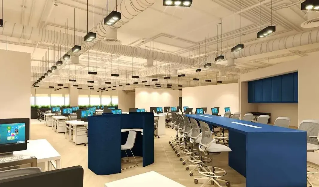 A modern, open-plan office in Singapore with rows of desks, privacy partitions, and a mix of task and ambient lighting.