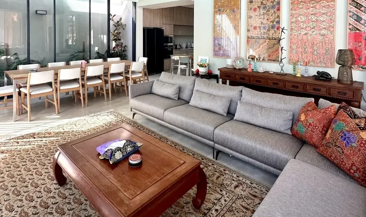 A bright and spacious modern living room in Singapore with a gray sofa, a wooden coffee table, and large-scale wall art.
