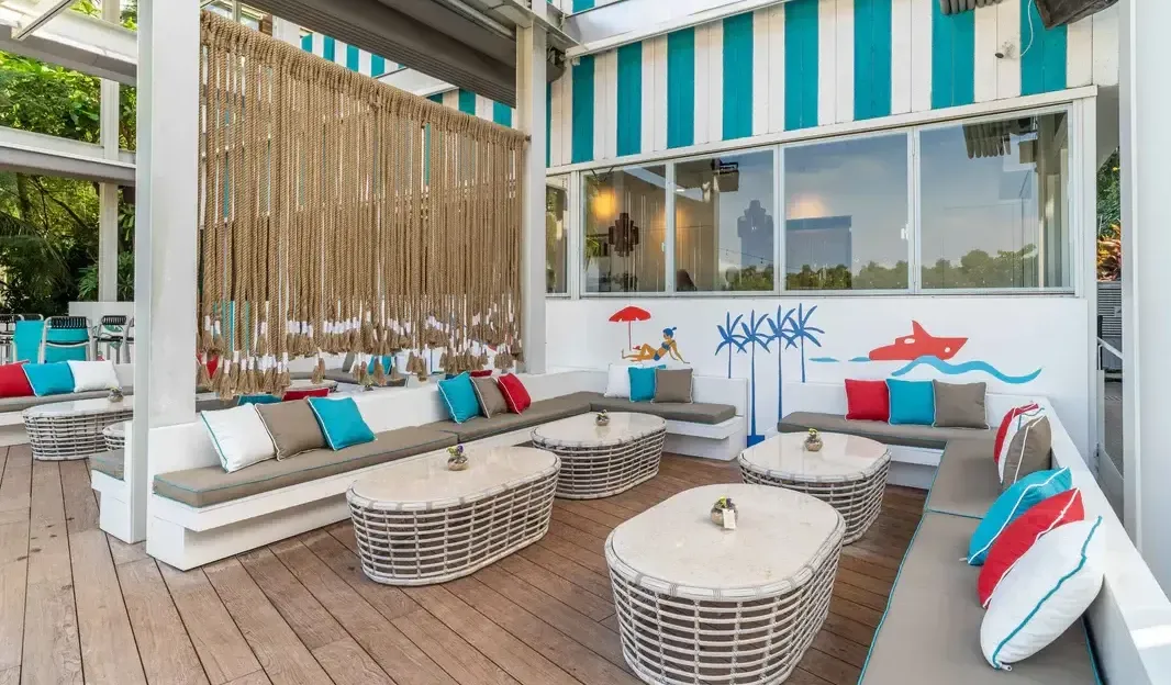 A bright and modern restaurant interior in Singapore with rows of tables, turquoise chairs, and a vibrant color palette.