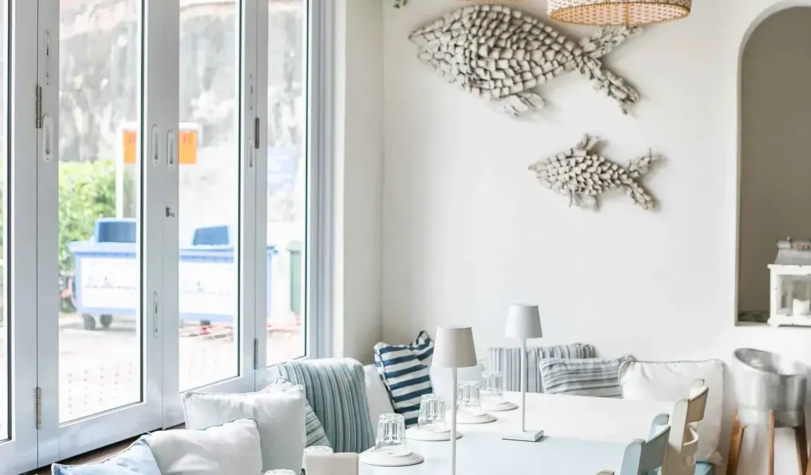 A bright and serene living space with white and blue decor, abundant natural light, and a coastal-inspired aesthetic.