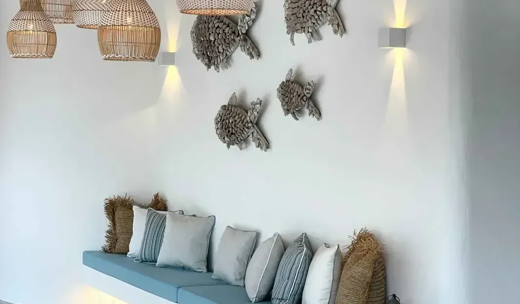 A modern, coastal-inspired lounge area with a built-in bench, pillows, and decorative fish wall art.
